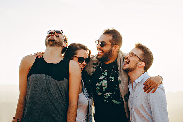 Três homens e uma moça se abraçando e sorrindo